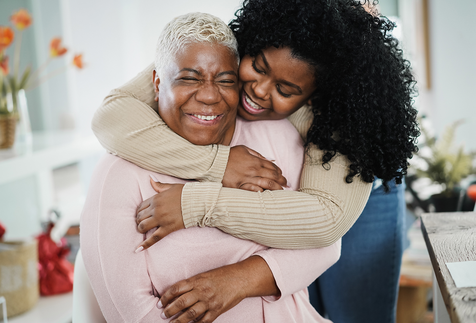 Two women sharing a joyful, warm embrace and laughter.